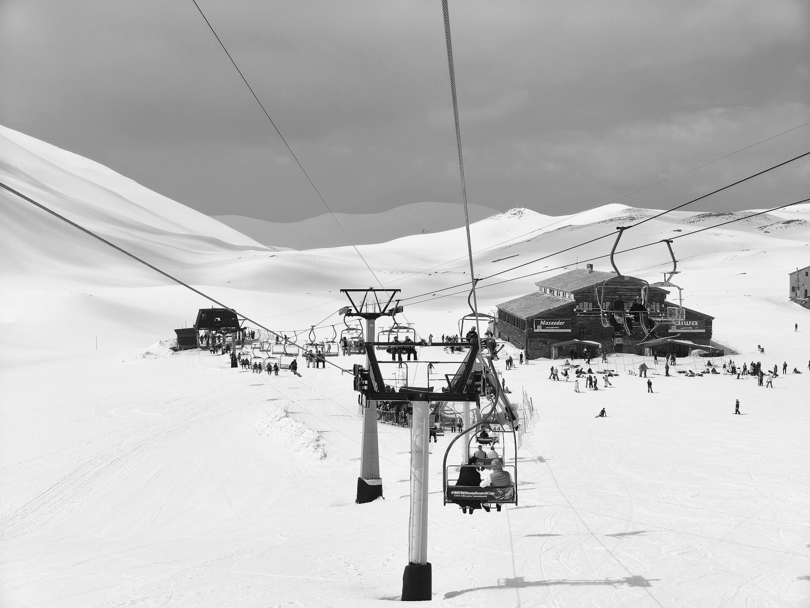 Ski lift ascending snowy mountain with buildings and buildings.