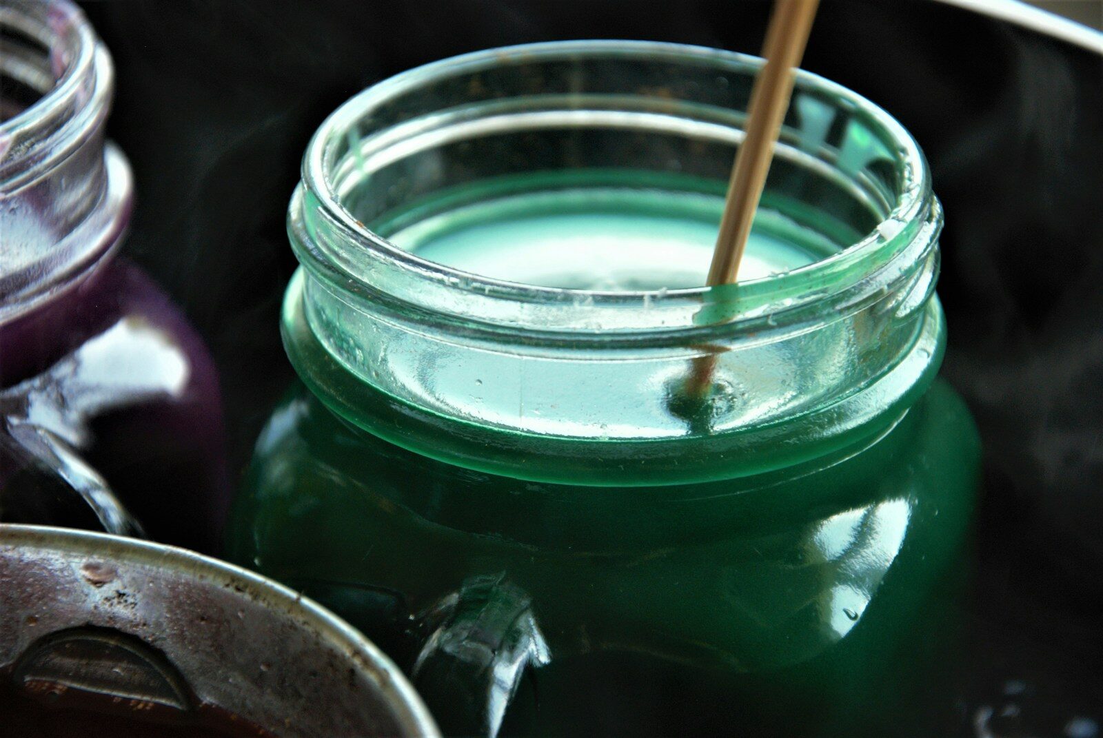 a jar of liquid with a wooden stick sticking out of it